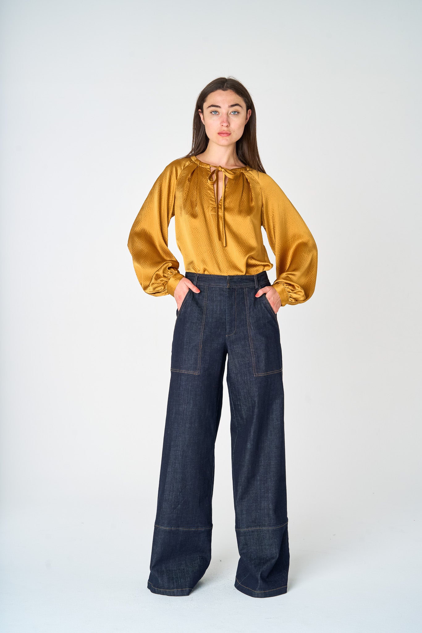 Woman standing in Hepburn Trousers with deep pockets and wide legs.