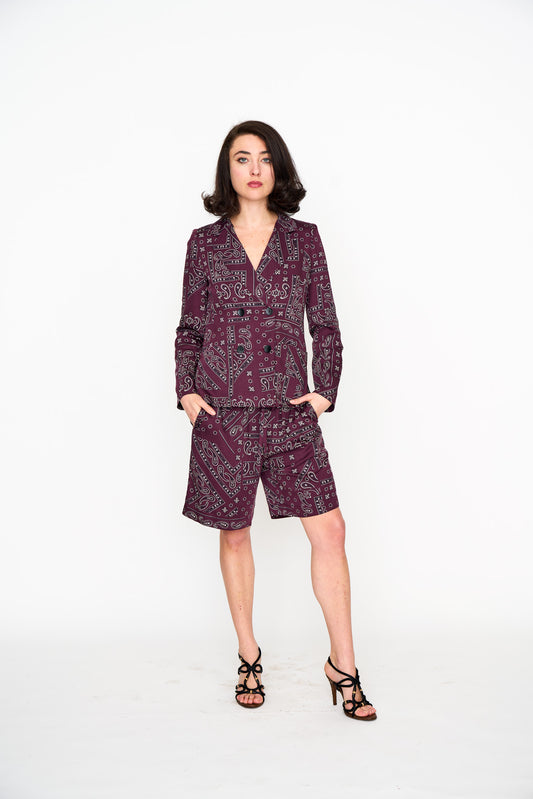 Woman wearing a dark red patterned suit jacket and matching shorts