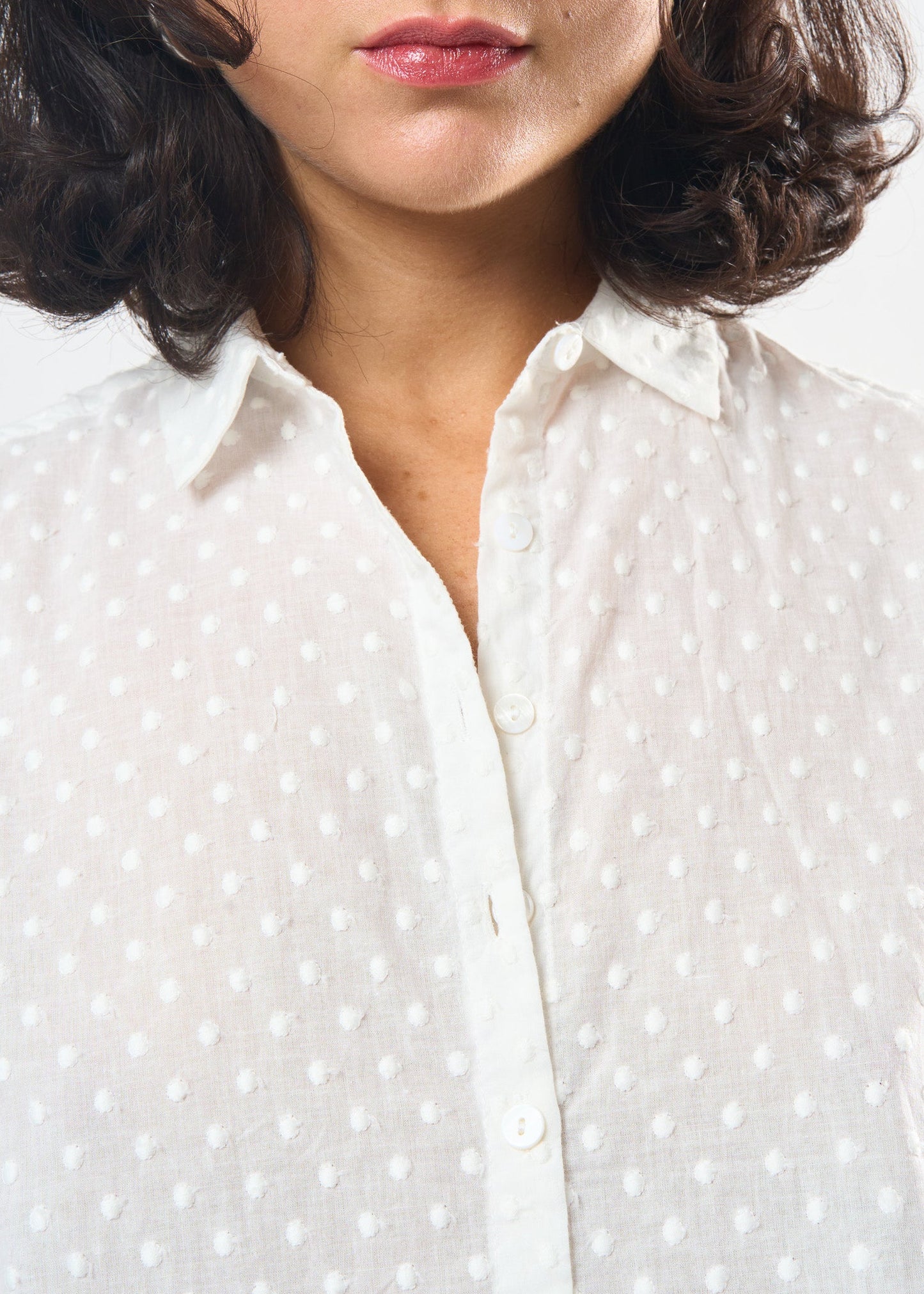 Close-up of a person wearing a white polka dot shirt with a blurred background