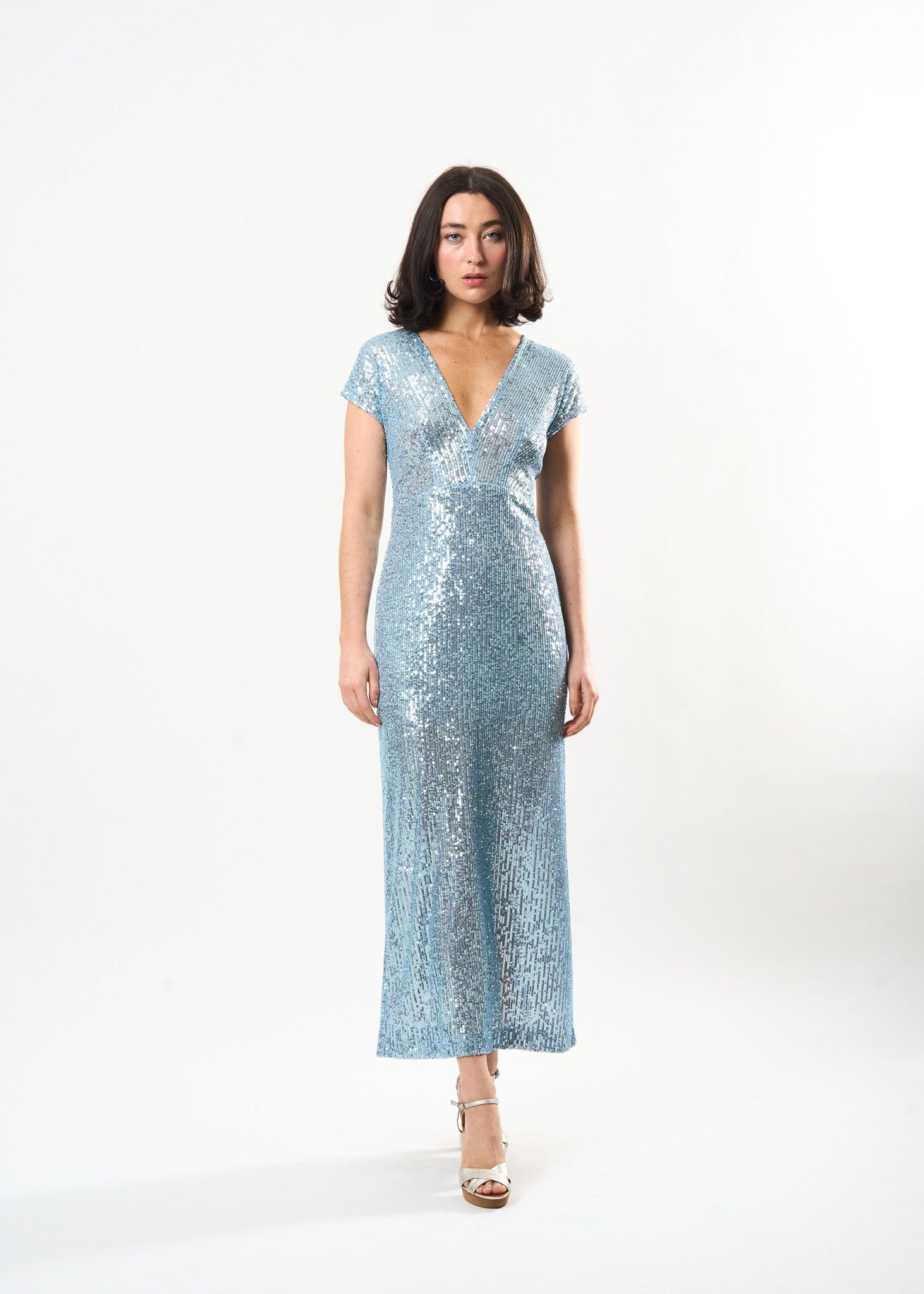 Woman wearing a light blue sequin dress on a white background
