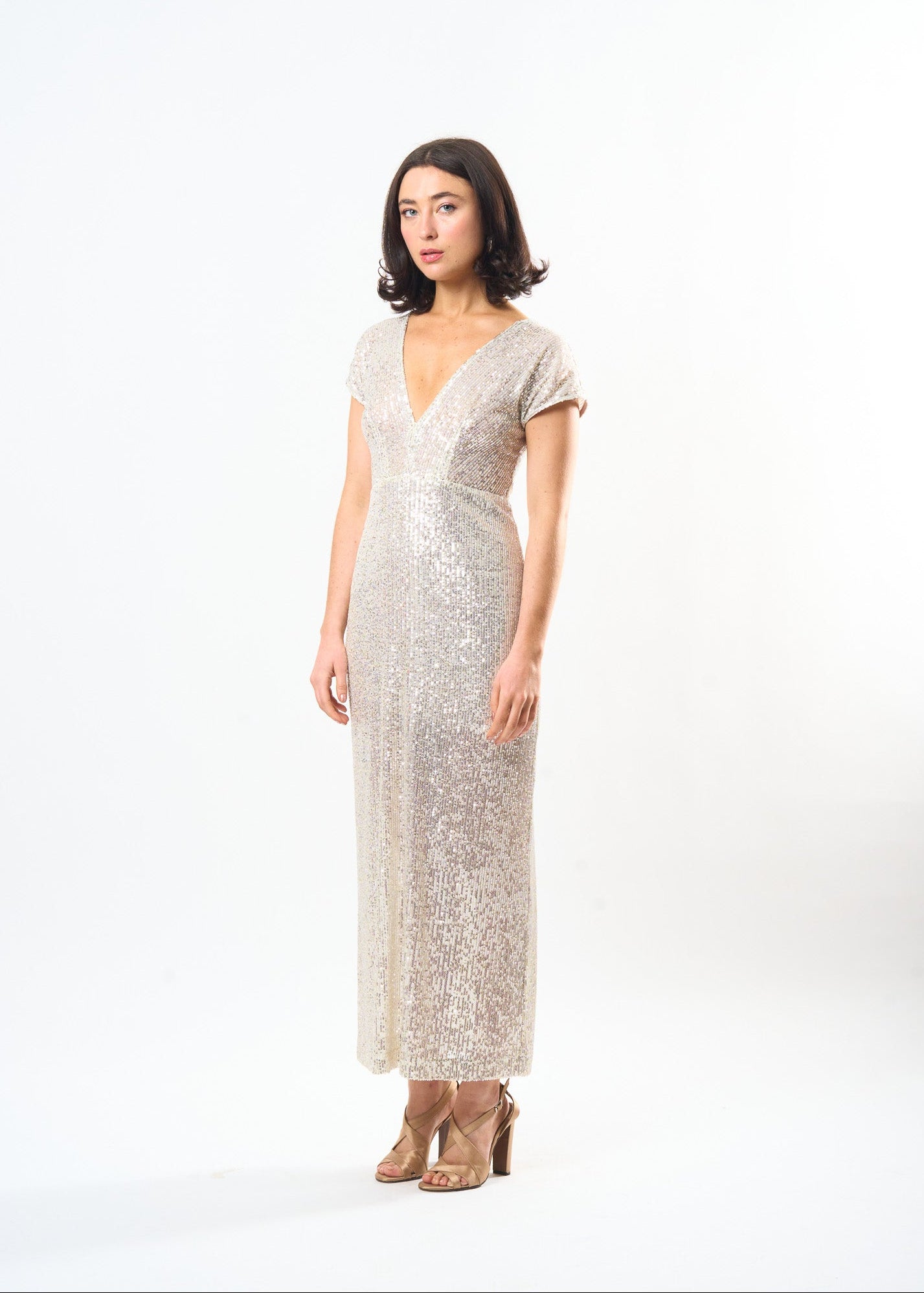 Woman wearing a sparkly silver dress on a white background