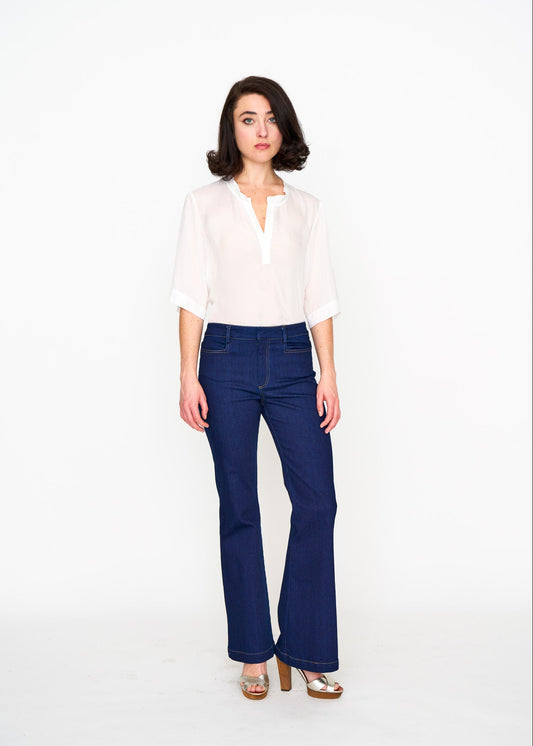 Woman wearing a white silk blouse tucked into blue bootcut jeans