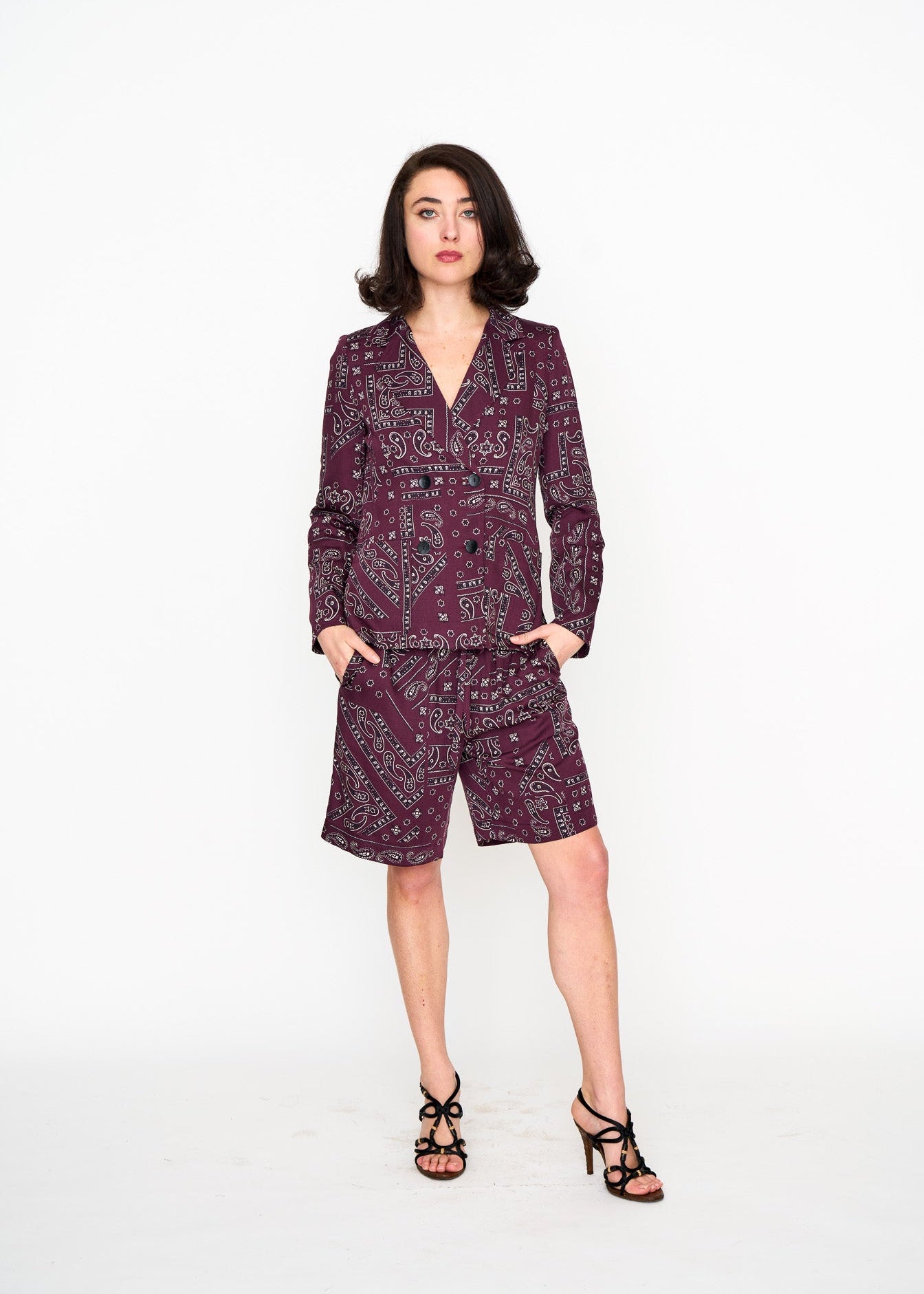 Woman wearing a dark red patterned suit jacket and matching shorts